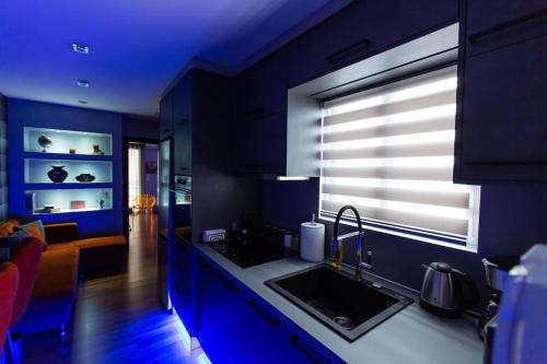 a blue kitchen with a sink and a window at Suite Vali in Nafpaktos