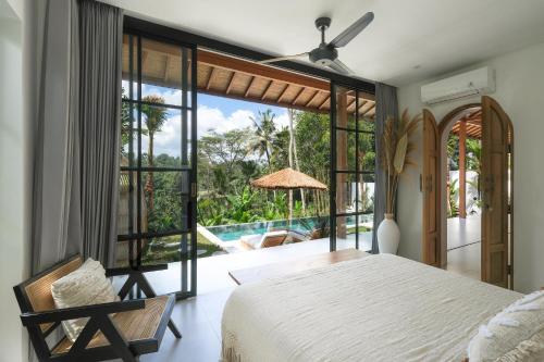 a bedroom with a bed and a view of a pool at Villa Lestari Ubud in Tegalalang