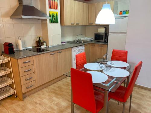 a kitchen with a dining table and red chairs at Apartamentos Alcañiz, Marisol in Alcañiz