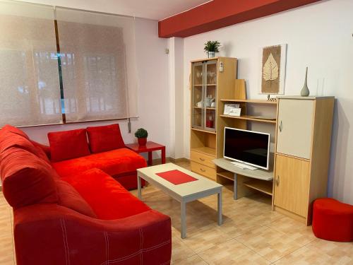 a living room with a red couch and a television at Apartamentos Alcañiz, Marisol in Alcañiz