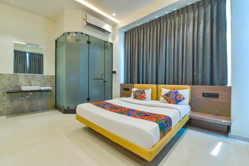 a bedroom with a large bed and a shower at FabHotel Gold Palace Inn in Surat