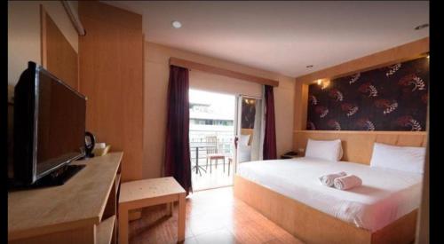 a bedroom with a bed and a desk with a television at new pind balluchi inn in Pattaya