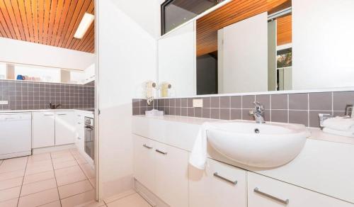 La salle de bains blanche est pourvue d'un lavabo et d'un miroir. dans l'établissement Nautilus Resort Apartment 162 Solitary Islands Way 8, à Sapphire Beach