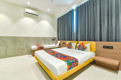 a bedroom with two beds and a window at FabHotel Gold Palace Inn in Surat