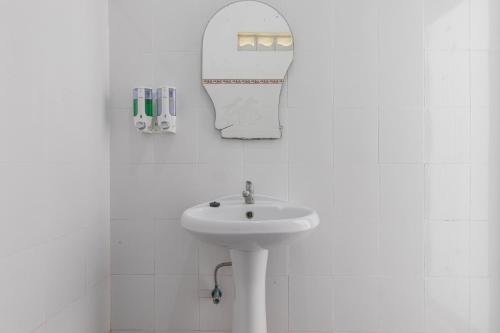 Un baño blanco con lavabo y espejo. en Nyuh Kadah Guest House, en Nusa Penida