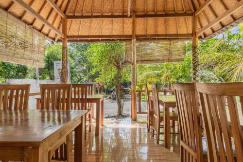 un restaurante con mesas de madera y sillas bajo un pabellón en Nyuh Kadah Guest House, en Nusa Penida