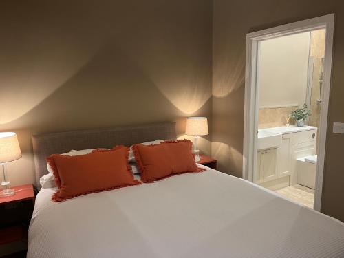 a bedroom with a large bed with orange pillows at The Mulberry Apartment at Langford Hall in Newark upon Trent
