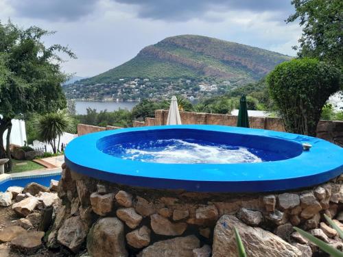 a blue pool in a stone wall with a mountain in the background at El Shadai Guest House & Spa Hartbeespoort in Hartbeespoort