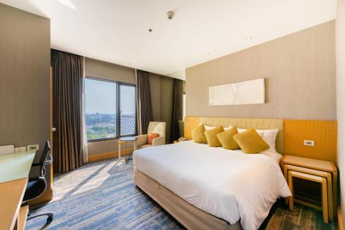 a hotel room with a large bed with yellow pillows at Grand Richmond Stylish Convention Hotel in Nonthaburi