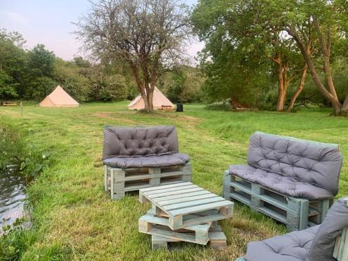 dos sillas, una mesa y tiendas en un campo en Camping By The River 