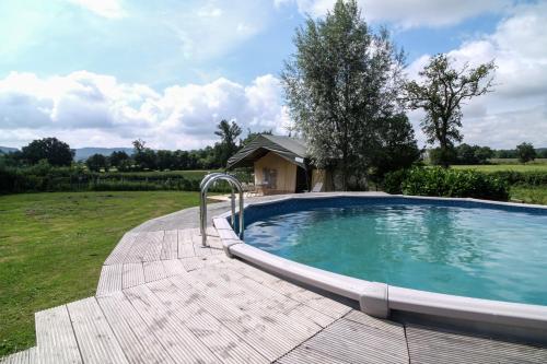 a swimming pool in a field with a house at A la Bonne Heure in Pionsat