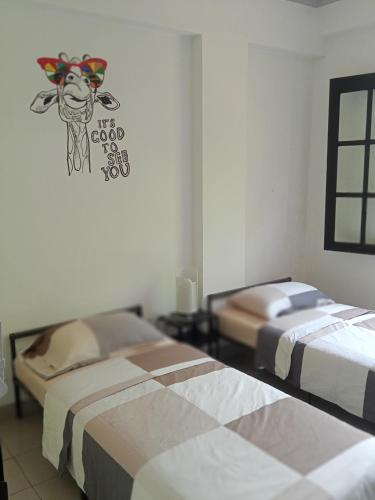 um quarto com duas camas com uma vaca na parede em CONDOMINIUM LIPPO PANTAI CARITA em Carita