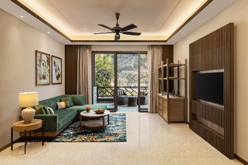 a living room with a green couch and a television at Taj Corbett Resort and Spa Uttarakhand in Rāmnagar
