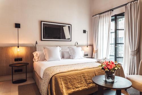 um quarto de hotel com uma cama e uma mesa com flores em Sant Francesc Hotel Singular em Palma de Maiorca