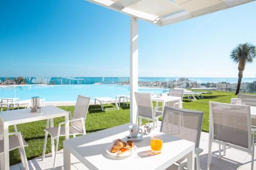 un patio con tavoli e sedie e vista sulla piscina di Villa Coppitella, rooms & apartments a Vieste