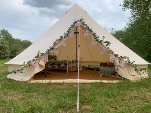 a large white tent with flowers on it in a field at Camping By The River in Sutton Courtenay