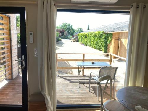 une porte menant à une terrasse avec une table et des chaises. dans l'établissement Chalet 2 pers « chez Jojo », à Sérignac