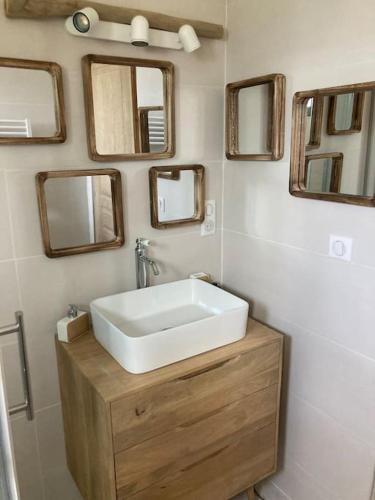 une salle de bain avec un lavabo et des miroirs au mur dans l'établissement Chalet 2 pers « chez Jojo », à Sérignac