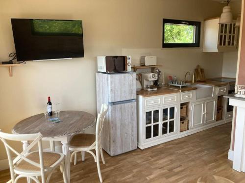 La cuisine est équipée d'une table, d'un four micro-ondes et d'un réfrigérateur. dans l'établissement Chalet 2 pers « chez Jojo », à Sérignac