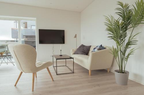 sala de estar con sofá, silla y planta en Nordic Swan Aparthotel with Panoramic Seaview, en Tórshavn