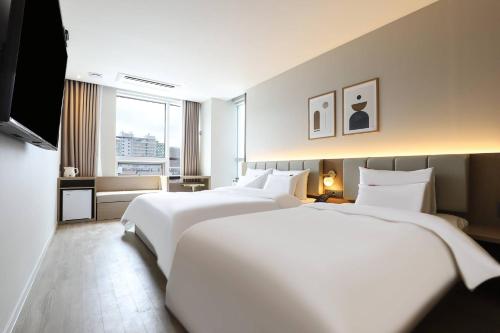 a hotel room with two beds and a window at Wonju Brown Dot Hotel Corporate Business in Wonju