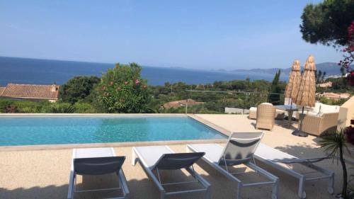 einen Pool mit Stühlen und einem Tisch daneben in der Unterkunft Villa Corse Vue mer et piscine in Porticcio