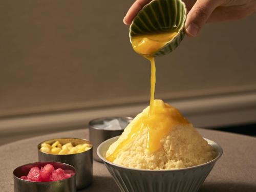a person drizzling mustard onto a bowl of food at ASAI Kyoto Shijo in Kyoto