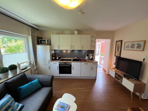 een woonkamer met een bank en een keuken bij Steerenklipp Kieker Bungalow 2 in Borkum