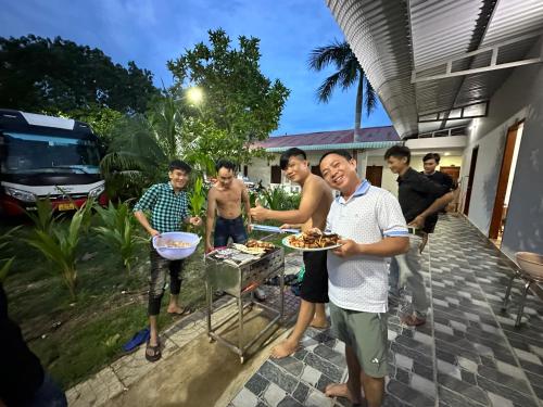 un grupo de hombres parados alrededor de una parrilla con comida en Hotel Như Ý Hồ Tràm, en Thuận Biên