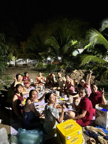 a group of people sitting around a table on the beach at Hotel Như Ý Hồ Tràm in Thuận Biên