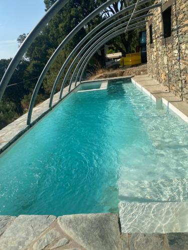 uma piscina de água azul com uma ponte de metal em Chambres d’hôtes A Casa Di Marigaby em Barbaggio