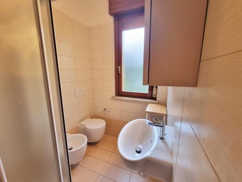 baño con lavabo y aseo y ventana en Appartamenti Aurora, en Grado