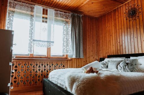 a bedroom with wooden walls and a bed with a cat laying on it at Tatra House z Jacuzzi in Poronin