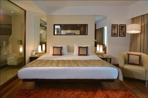 a bedroom with a large bed and a bathroom at Majestic Court Sarovar Portico in Navi Mumbai