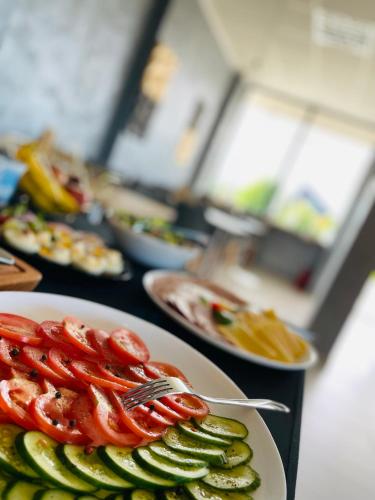ein Tisch mit Tellern voller Essen mit Tomaten und Gurken in der Unterkunft Boutique 78 by Housine in Zator