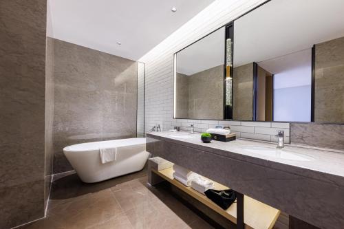 un bagno con vasca, lavandino e specchio di 东莞凤岗众恒隆逸扉酒店 a Dongguan