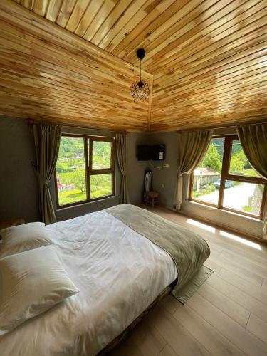Bizim O'ra Küme Evleri & Bungalov في ماتشكا: غرفة نوم بسرير كبير بسقف خشبي