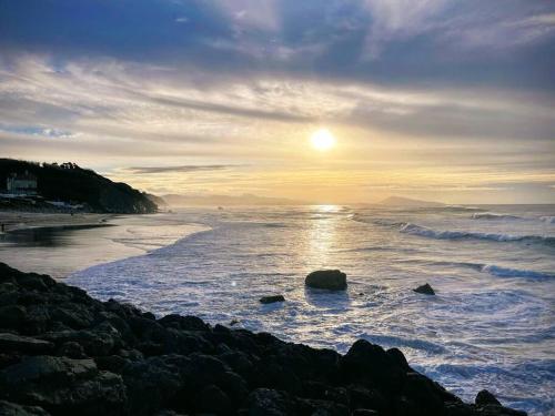 - un coucher de soleil sur une plage avec l'océan et les rochers dans l'établissement Bord de Mer - Adorable maison au calme - 6 pers., à Biarritz