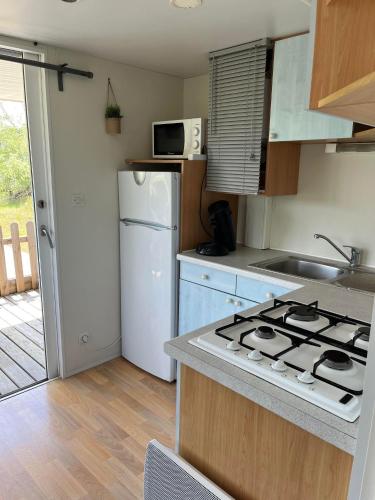 une cuisine avec une cuisinière et un réfrigérateur dans l'établissement Bungalow à l'asinerie, à Jau-Dignac-et-Loirac