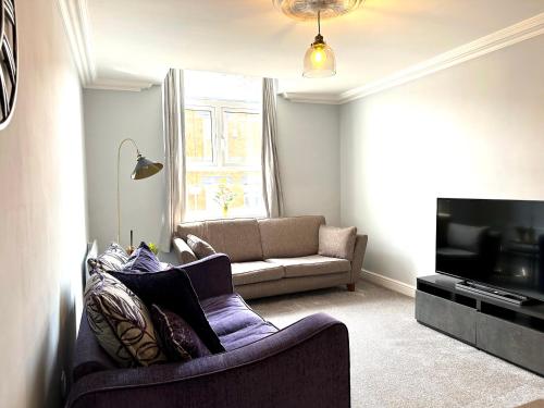 a living room with a couch and a tv at Comfortable City Apartment in Derby