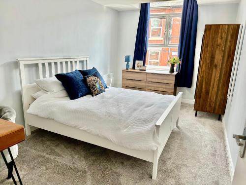 1 dormitorio con cama blanca y almohadas azules en Comfortable City Apartment en Derby