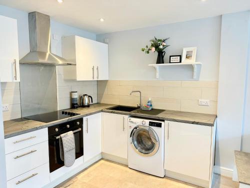 biała kuchnia z pralką w obiekcie Comfortable City Apartment w mieście Derby