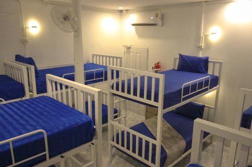 Pokój z 4 łóżkami piętrowymi i niebieską pościelą w obiekcie World Citizen Hostel w mieście Baan Tai