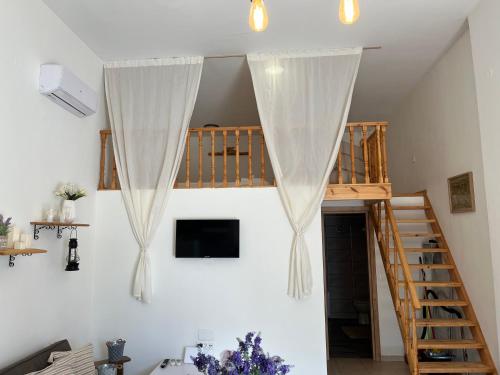 a room with white walls and a staircase with curtains at Irene’s house in Koskinou