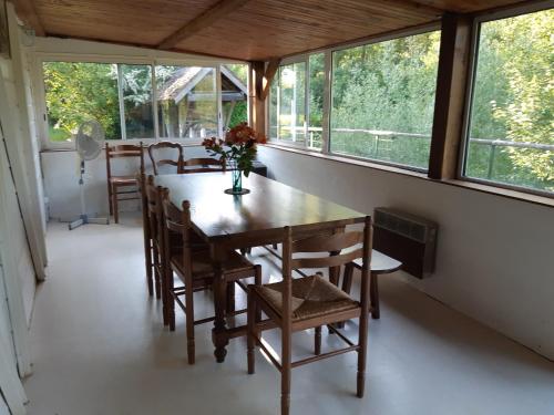 une salle à manger avec une table, des chaises et des fenêtres dans l'établissement Cabane avec plan d'eau privatif, à Les Hayes