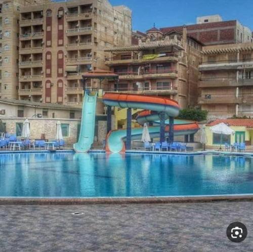 a swimming pool with a water slide in front of a building at Alzohour Family condo with panoramic sea view in Alexandria