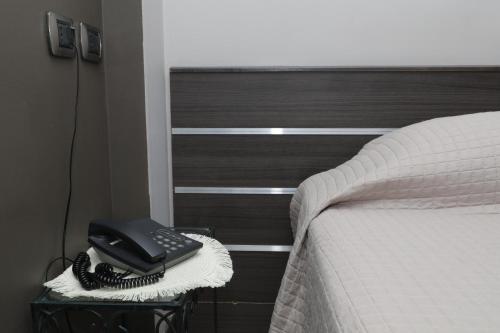a black phone sitting on a table next to a bed at Hotel Residence Aurora in Paderno Dugnano