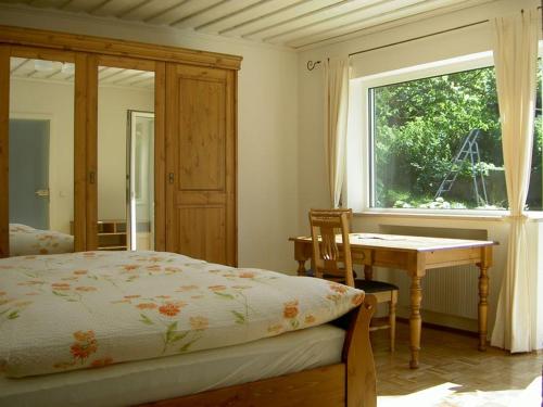 a bedroom with a bed and a table and a window at Gästehaus Ehrlich in Prien am Chiemsee