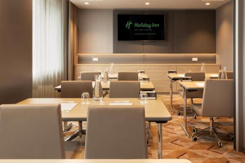 a conference room with tables and chairs and a tv at Holiday Inn - Eindhoven Airport by IHG in Eindhoven