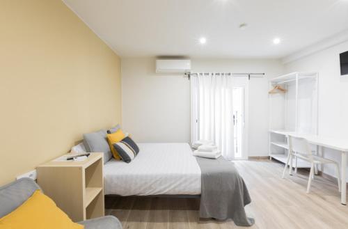 Habitación pequeña con cama y escritorio. en Hostal Oliveta, en Barcelona